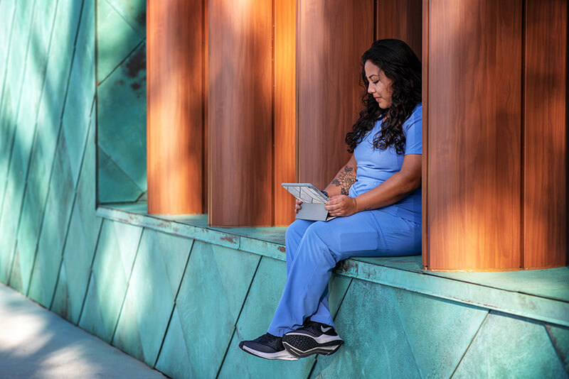 health science student in scrubs sitting with laptop